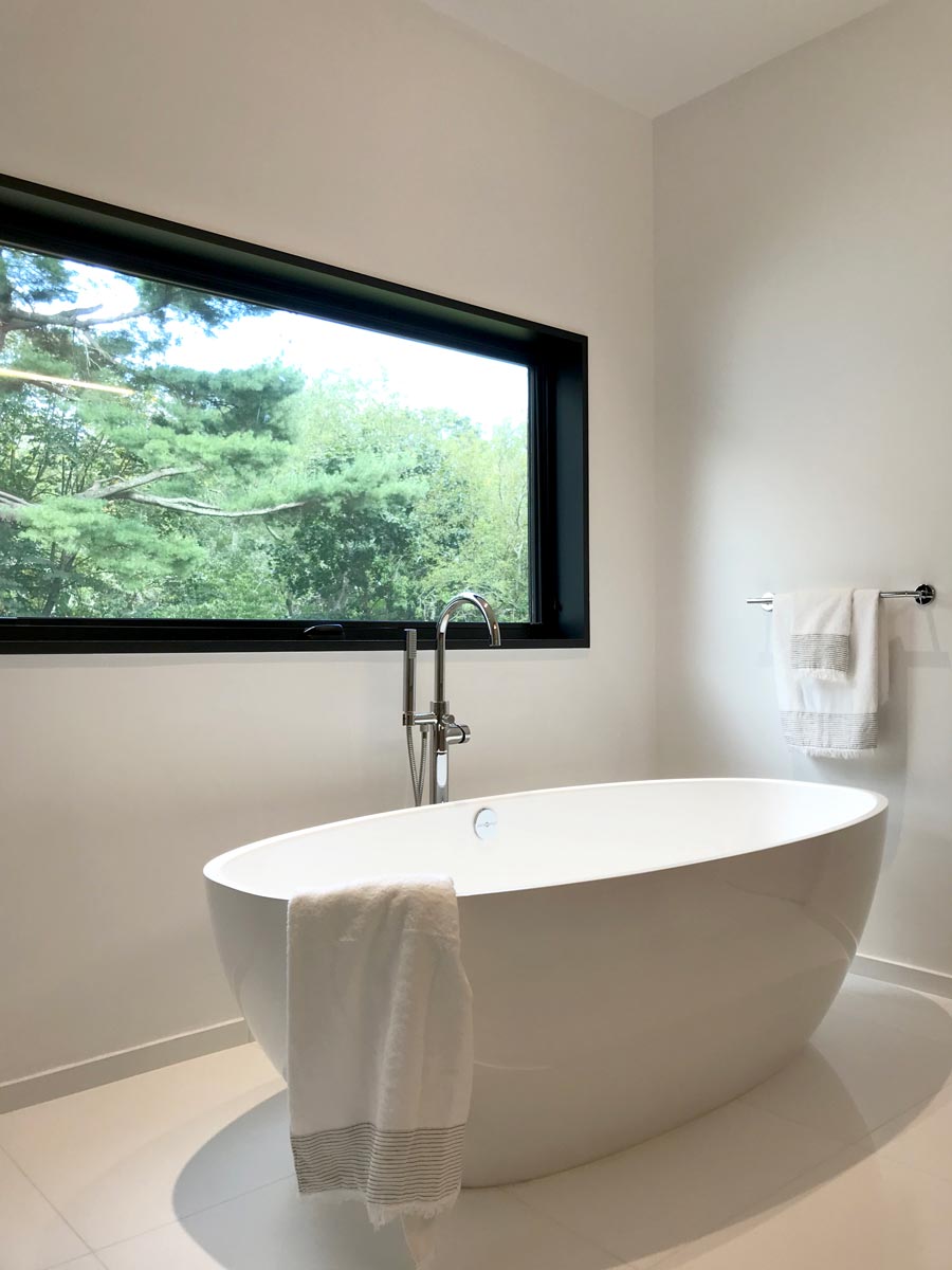 minimal white bathroom with freestanding tub and scenic li ny views