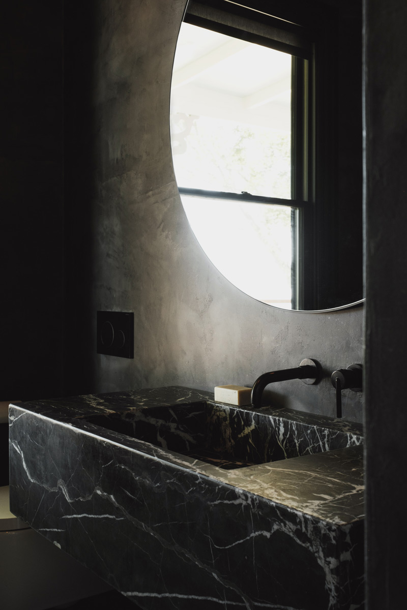black plaster microcement wall treatment with black marble bathroom vanity