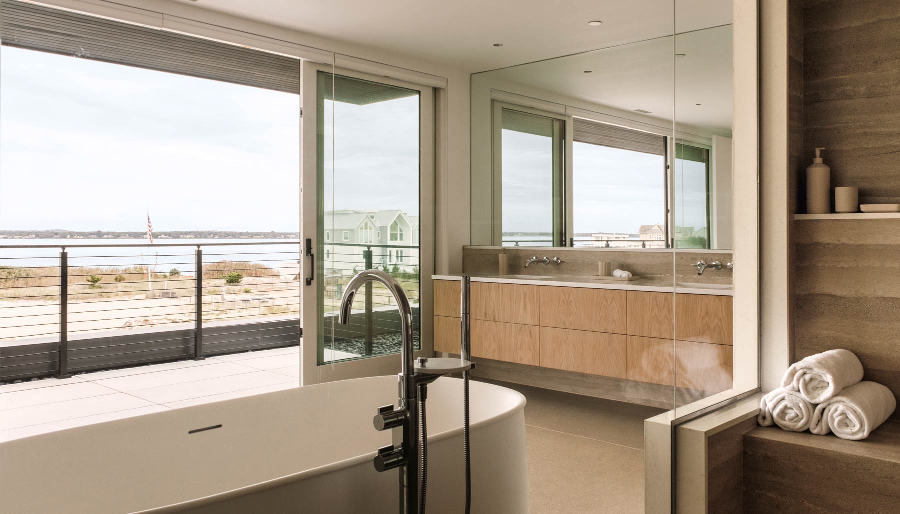 luxury spa-like modern bathroom with hampton bay views and floating tub