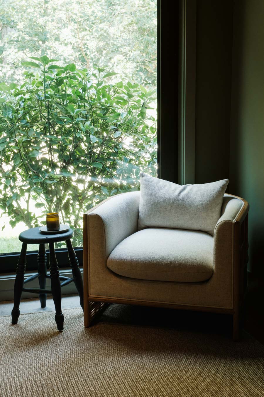 cozy reading nook with deep green wall and warm natural furnishings