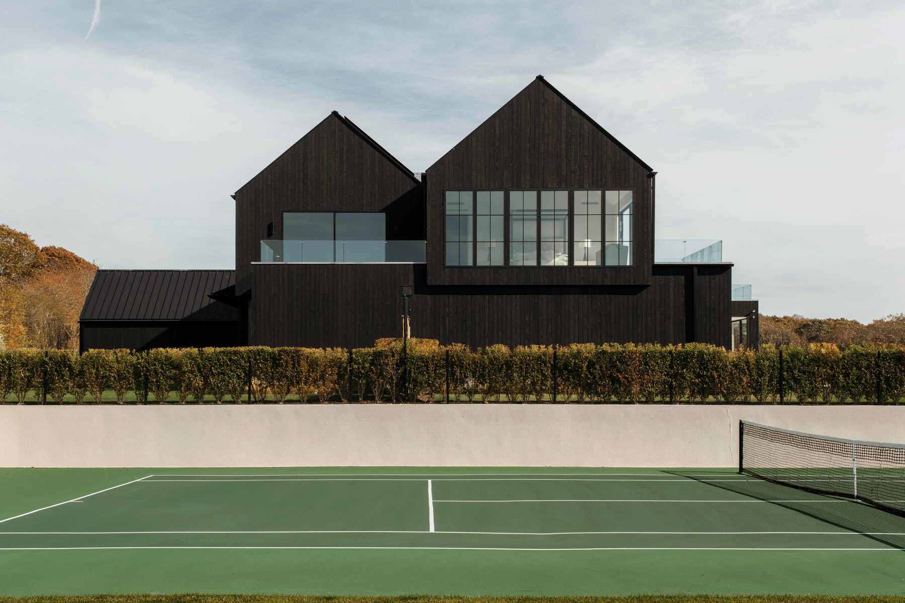 gabled contemporary black farmhouse design with sunken tennis court