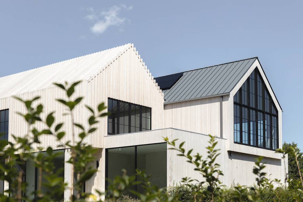 hamptons modern farmhouse architecture with light wood siding and tin metal roof